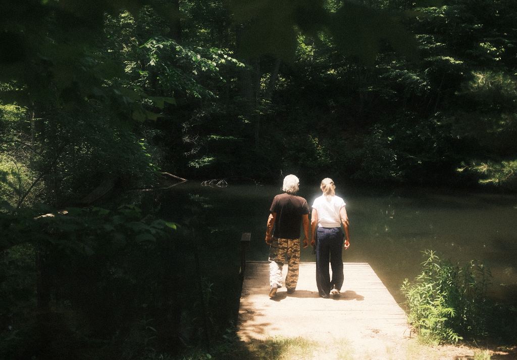 Two people walking out on the dock over the forest pond
