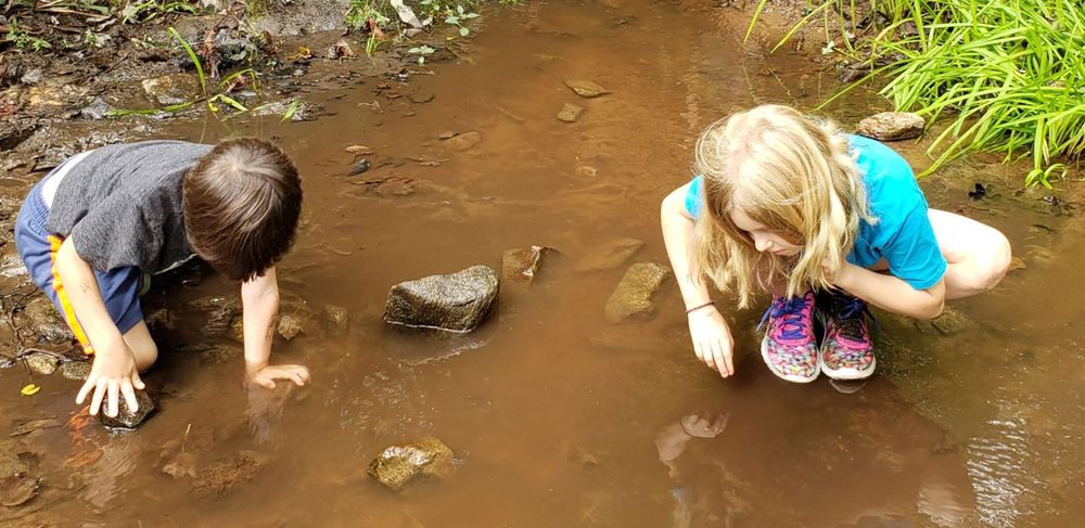 Two children exploring the stones in a creek